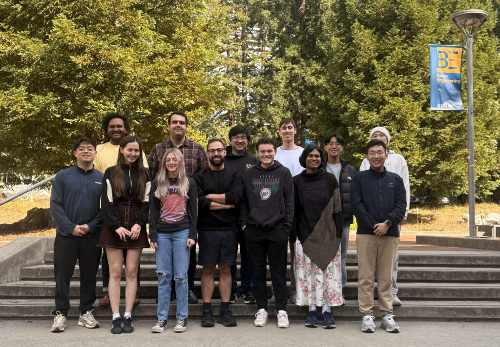 A group of people stand in front of stairs with redwood trees in the background
